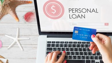 Person holding a credit card and a laptop screen that shows the text "Personal Loan".