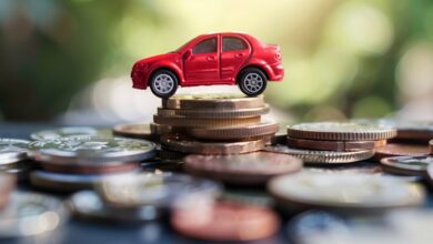A red toy car on a stack of coins.